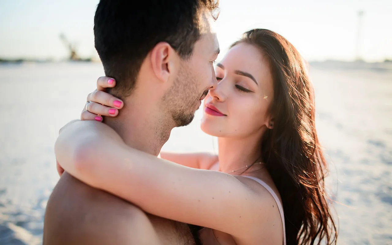 An adult couple embracing by the water for herpes singles dating